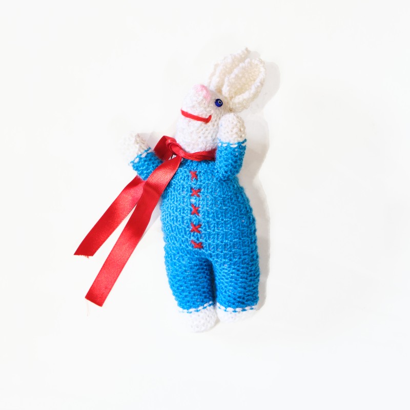 Knitted light blue doll, rabbit design, with red ribbon around the neck