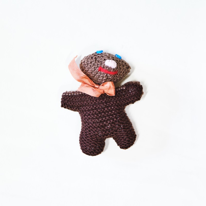 Knitted smiling doll, brown color with orange ribbon around the neck